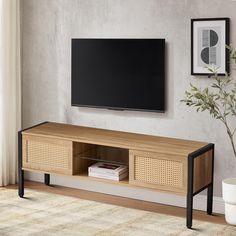 a flat screen tv sitting on top of a wooden entertainment center next to a plant