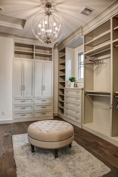 a large walk in closet with lots of drawers and white furniture on top of it