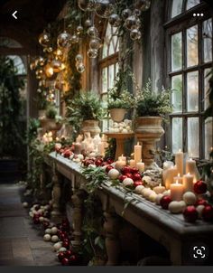 a long table covered in lots of candles and christmas decorations next to a large window