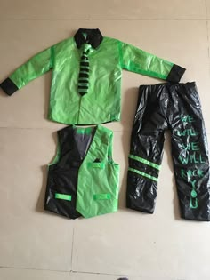 two pieces of green and black clothing laid out on top of the floor next to each other