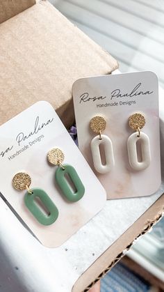 two pairs of green and white earrings sitting on top of a table next to a box