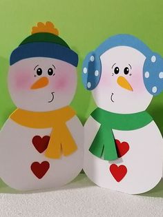 two paper snowmen are standing next to each other