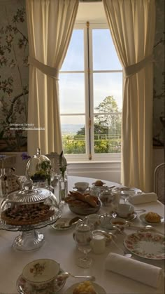 a table with plates and cups on it in front of a window