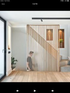 an image of a room with stairs and wooden slats on the wall, as well as a person sitting at the door