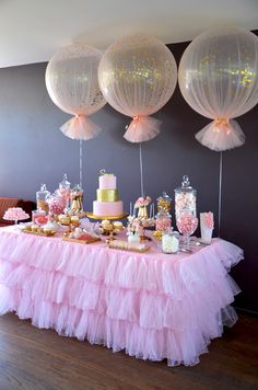 a table topped with lots of desserts and balloons