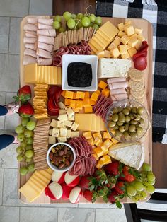 a platter with cheese, meats, fruit and crackers is shown on a table