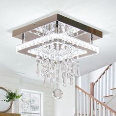 a chandelier hanging from the ceiling in a living room with white walls and hardwood floors