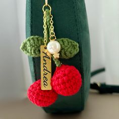 a crocheted keychain with two cherries and a name tag attached to it