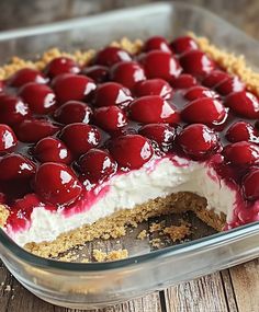 a cherry cheesecake in a glass dish on a wooden table