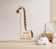 the wooden giraffe is next to two stuffed animals in front of a white wall