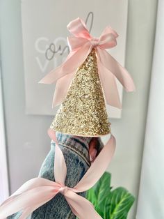 a pink and gold party hat on top of someone's jeans with a bow