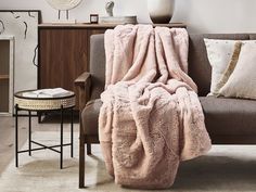 a living room with a couch, chair and table covered in blankets on the floor