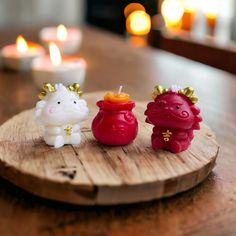 three small candles sitting on top of a wooden tray next to each other in the shape of animals