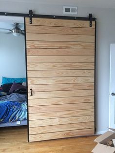 an open sliding door in a bedroom next to a bed and a dresser with boxes on the floor