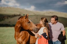 a man and woman standing next to a brown horse