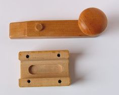 two wooden pegs and a ball on a white surface