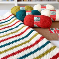 several balls of yarn sitting on top of a table next to a crocheted blanket