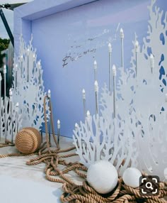 an artistic display with white decorations and rope on the ground in front of a blue wall