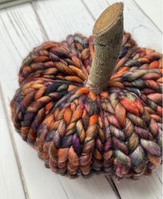 a yarn pumpkin sitting on top of a white wooden floor next to a piece of wood