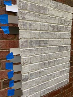 blue tape is taped to the side of a brick wall with white and gray paint