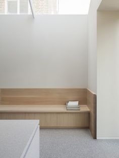 an empty room with white walls and wooden bench