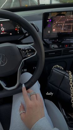 a woman driving a car with her hand on the steering wheel