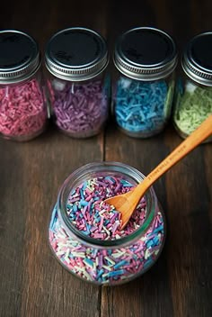 colorful sprinkles in glass jars with wooden spoon