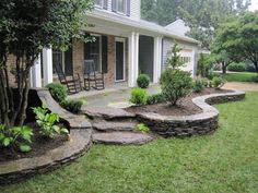 a stone patio with steps leading to the front door and back yard area, surrounded by green grass