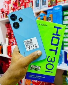 a person holding up a cell phone in front of a store shelf with other items