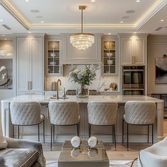 an elegant kitchen with marble counter tops and white cabinets, along with gray upholstered chairs