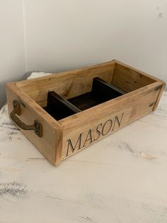 a wooden box sitting on top of a white table with the word mason written in it