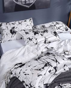 an unmade bed with black and white paint splattered on the comforter