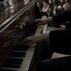 a person playing the piano in front of an audience with their hands on the keys