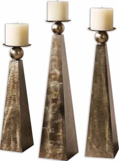 three tall metal candlesticks with white candles