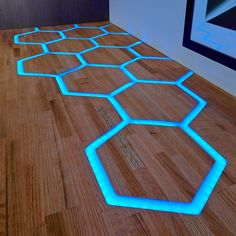 a wooden floor with blue light in the middle and hexagonal shapes on it