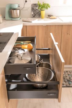 an open drawer in a kitchen with pots and pans