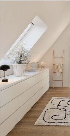 an attic bedroom with white walls and wooden flooring, large rug on the floor