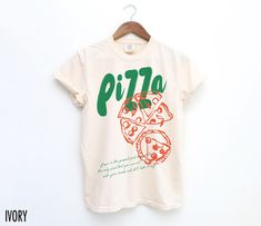 Satisfy your style cravings with this vintage-inspired Pizza tee! Featuring a bold pizza graphic this shirt adds a slice of retro fun to any casual look. The text at the bottom reads, " Pizza is the perfect food because it is the only food that you can eat with your hands and still look classy."  We use professional quality DGT printing on all our apparel. Direct-to-garment, or DTG, is a high quality printing method that sprays ink directly onto the garment so there is no peeling or cracking. Th Unisex Vintage Crew Neck T-shirt, Unisex Retro T-shirt With Text Print, Vintage Text Print Crew Neck Shirt, Unisex Vintage Short Sleeve Shirt, Retro Cotton Shirt With Text Print, Unisex Vintage Cotton Shirt, Vintage Unisex Tops With Funny Print, Retro Cotton Slogan Shirt, Retro Unisex Short Sleeve Shirt