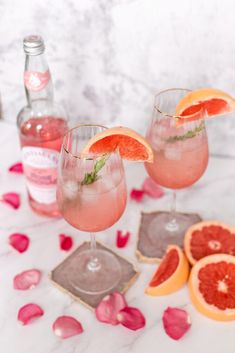 two glasses filled with pink grapefruit and garnished with mint on the side