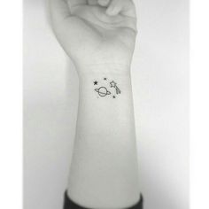 a person's arm with a small penguin and stars tattoo on the left wrist