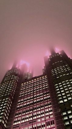 some very tall buildings in the foggy night