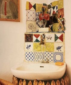 a bathroom sink sitting under a mirror next to a wooden rack with pictures on it