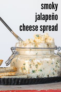 a glass jar filled with cheese and crackers on top of a table next to bread