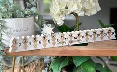 a wooden ruler sitting on top of a table next to white flowers and potted plants