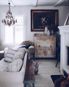 a living room filled with furniture and a chandelier hanging from the ceiling next to a fire place