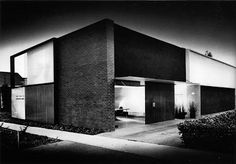 an old black and white photo of a modern house at night with the lights on