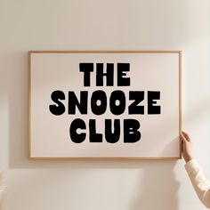 the snooze club is displayed on a wall above a woman's hand