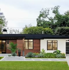 a modern house in the middle of a lush green yard