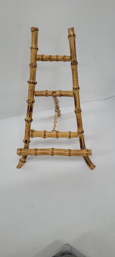 a small wooden ladder with chains hanging from it's sides on a white surface