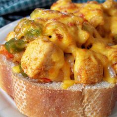 a piece of bread topped with cheesy chicken and peppers on a white plate